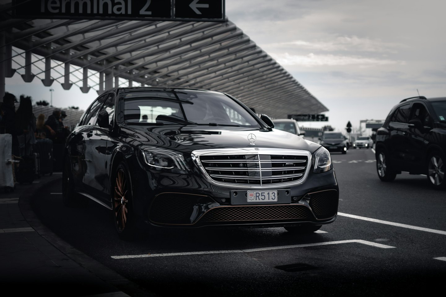 Juodas "Mercedes" sedanas, pastatytas oro uosto terminale po stogine.