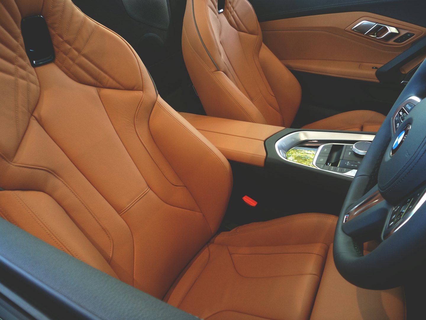 Modernus automobilio salonas su rudos odos sėdynėmis ir prietaisų skydeliu.